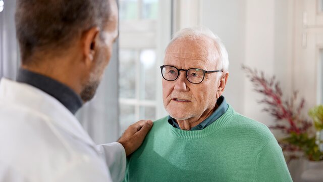Ein Arzt spricht mit einem älteren Patienten. | © AstraZeneca2003