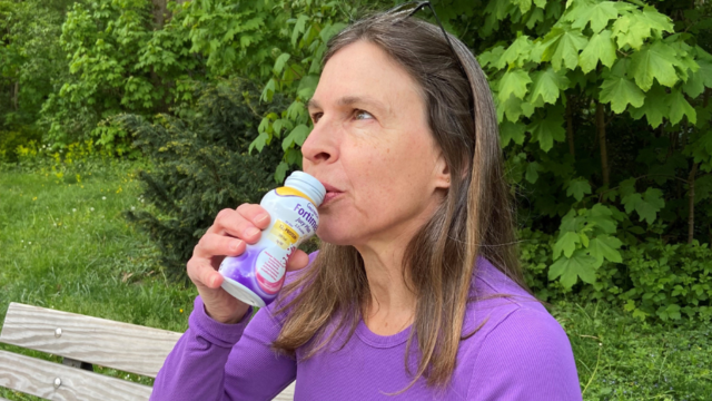 Eine Frau trinkt Fortimel Trinknahrung. | © Danone-Nutricia