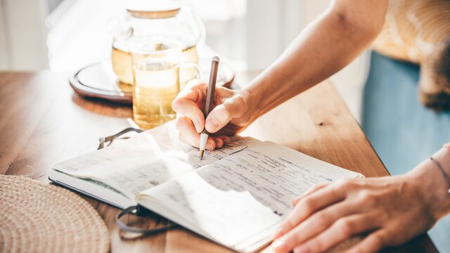 Eine Frau schreibt etwas in ein Notizbuch. | © Danone-Nutricia
