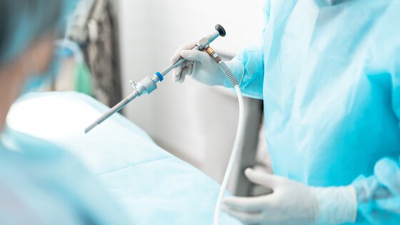 Nahaufnahme von mit sterilen Handschuhen, die ein laparoskopisches Instrument halten. | © AdobeStock-236325708