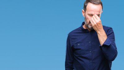 Ein Mann mittleren Alters reibt sich erschöpft Nase und Augen. | © AdobeStock-238798407