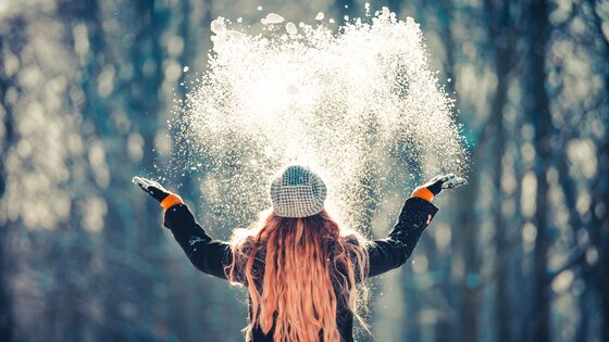 Eine Frau wirft Schnee in die Luft. | © AdobeStock_192967907