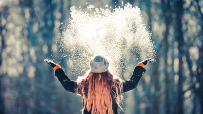 Eine Frau wirft Schnee in die Luft. | © AdobeStock_192967907