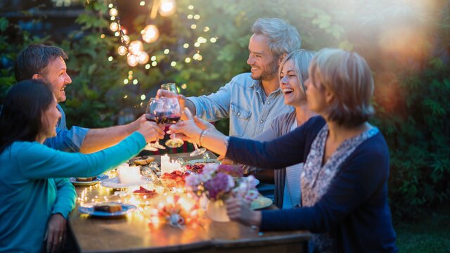 Fünd Menschen feiern abends gemeinsam in einem Garten. | © AdobeStock-202256771