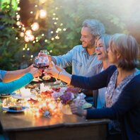 Fünd Menschen feiern abends gemeinsam in einem Garten. | © AdobeStock-202256771