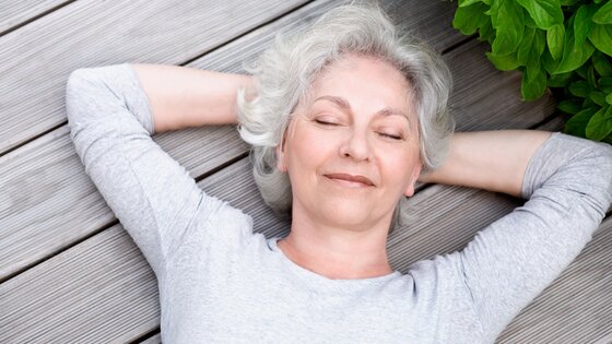 Eine ältere Frau liegt mit geschlossenen Augen auf dem Rücken.  | © AdobeStock-51331049