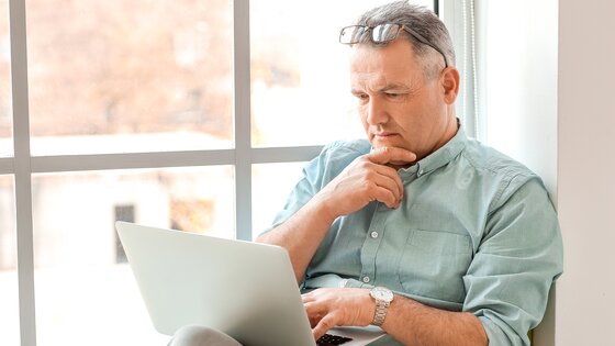 Ein älterer Mann informiert sich am Laptop | © AdobeStock-335750576