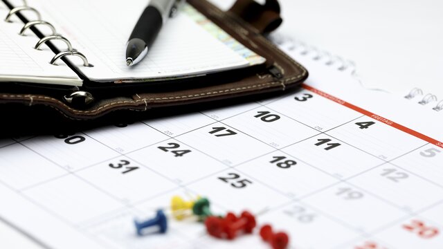 Detailaufnahme eine Kalenders auf dem ein Taschenkalender und ein Kugelschreiber liegen. | © AdobeStock-132537192