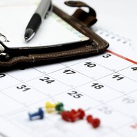 Detailaufnahme eine Kalenders auf dem ein Taschenkalender und ein Kugelschreiber liegen. | © AdobeStock-132537192
