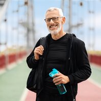 Ein älterer Mann steht lächelnd auf einer Brücke. | © AdobeStock_64602766